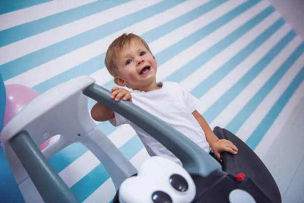Niedlicher Kleiner Junge Lächelt Während Spielzeugauto Sitzt Auf Hellem Hintergrund Stockbild