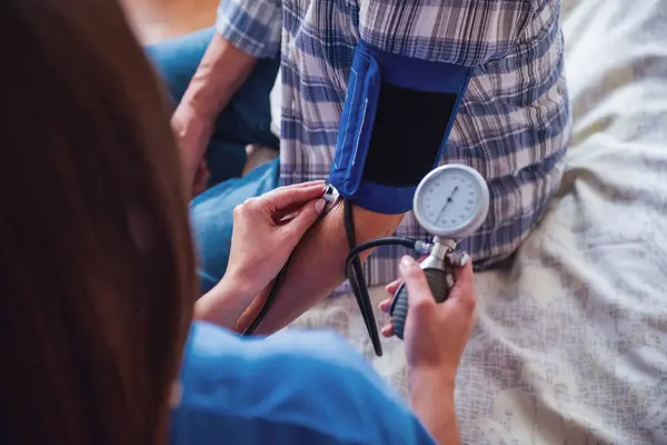 一个老人坐在医院病房 而医生是测量他的血压裁剪图像 — 图库照片