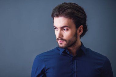 Yakışıklı emin işadamı ile kıl, koyu mavi gömlek, gri arka plan üzerinde arıyor