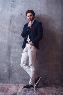 Gri arka plan üzerinde kamera poz yakışıklı emin işadamı ile kıl, takım, tam uzunlukta portresi