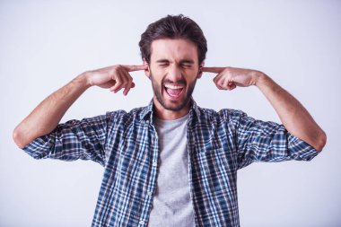 Yakışıklı sakallı adam rahat kıyafetler içinde onun kulaklarını kapatma ve çığlık, açık renkli