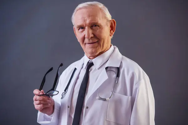 Handsome Old Doctor Medical Coat Holding Eyeglasses Looking Camera Gray — Stock Photo, Image