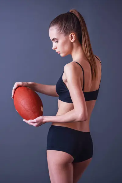 Όμορφο Κορίτσι Στο Sportswear Κρατάει Ένα Αμερικανικό Ποδόσφαιρο Μπάλα Γκρίζο Εικόνα Αρχείου