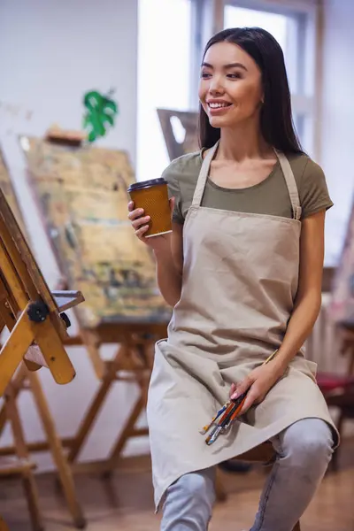 Young beautiful woman painting artist while working in a studio, smiling to the camera