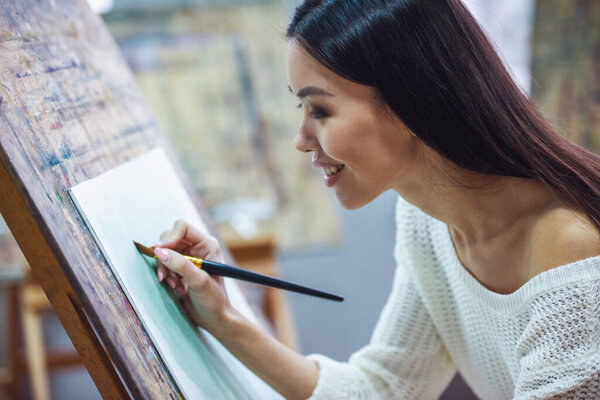 Молодая красивая женщина - художник живописи во время работы в студии
