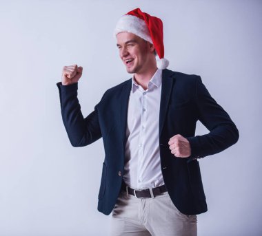 Yakışıklı olan takım elbise ve Santa şapka eller yükselterek ve gülüyor, üzerinde beyaz izole