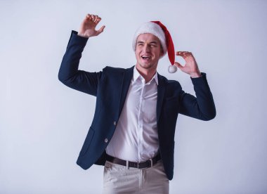 Yakışıklı olan takım elbise ve Santa şapka eller yükselterek ve gülüyor, üzerinde beyaz izole