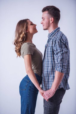 Güzel genç kaç rahat kıyafetler içinde el ele tutuşarak, birbirine bakarak ve gülümseyen izole üzerinde beyaz yakın duruyor