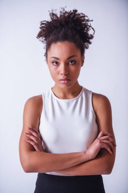 Güzel kız kameraya bakıyor kolları çaprazlanmış, beyaz tenli.