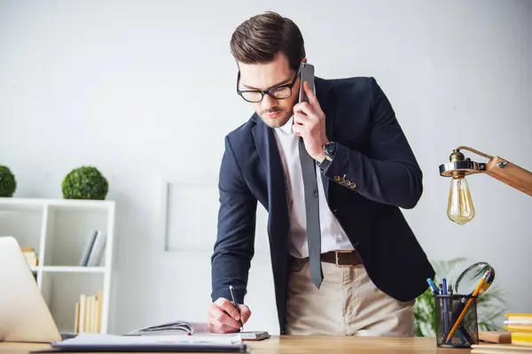 Handsome Businessman Eyeglasses Taking Notes While Talking Mobile Phone Office Stock Image