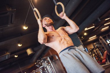 Genç ve güçlü bir adam spor salonunda egzersiz yaparken egzersiz yapıyor..