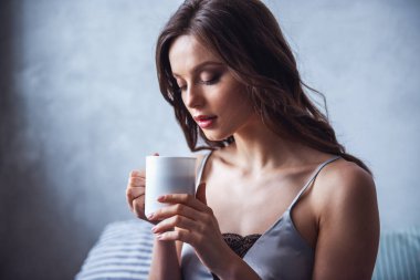 Güzel genç kız evde istirahat ederken bir fincan kahve/çay düzenliyor