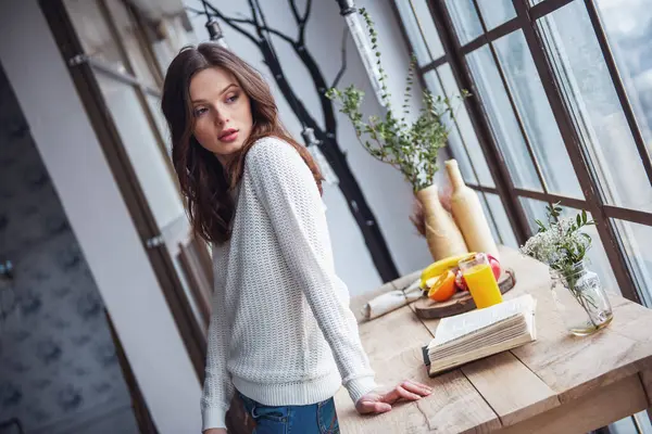 Güzel genç kız rahat kıyafetler içinde uzak evde ahşap masanın üzerine eğilerek arıyor