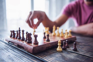 Satranç oynayan adamın kırpılmış görüntüsü, odaklı satranç tahtasının bir açısı, ahşap masa.