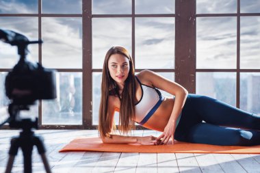 Büyük pencere arka planda evde fitness egzersiz çekim sırasında Genç güzel kız blogger