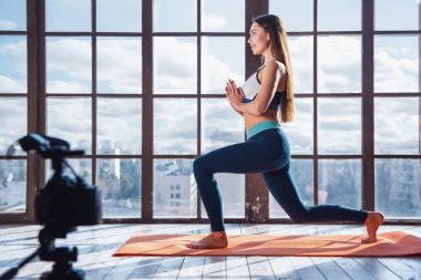 Büyük pencere arka planda evde fitness egzersiz çekim sırasında Genç güzel kız blogger