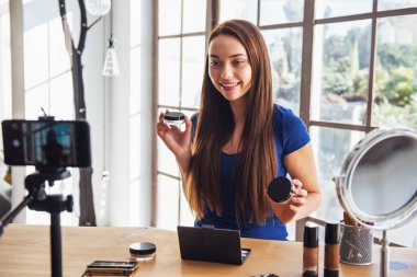 Evde kamera çekim yaparken kozmetik kullanarak genç güzel kadın blogger