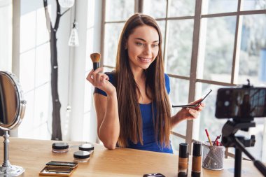 Evde kamera çekim yaparken kozmetik kullanarak genç güzel kadın blogger