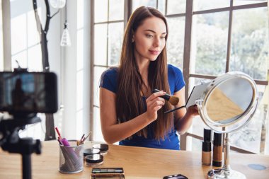 Evde kamera çekim yaparken kozmetik kullanarak genç güzel kadın blogger