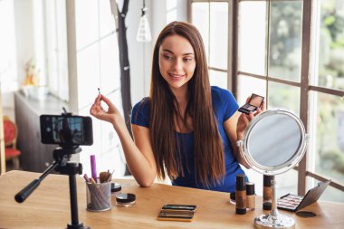 Evde kamera çekim yaparken kozmetik kullanarak genç güzel kadın blogger