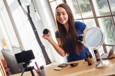 Evde kamera çekim yaparken kozmetik kullanarak genç güzel kadın blogger