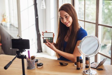 Evde kamera çekim yaparken kozmetik kullanarak genç güzel kadın blogger