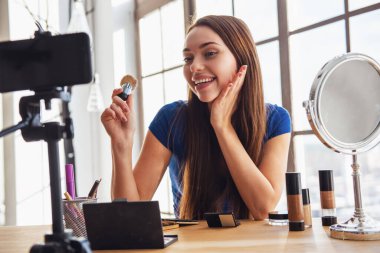Evde kamera çekim yaparken kozmetik kullanarak genç güzel kadın blogger