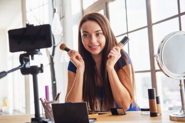 Evde kamera çekim yaparken kozmetik kullanarak genç güzel kadın blogger
