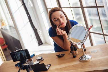 Evde kamera çekim yaparken kozmetik kullanarak genç güzel kadın blogger