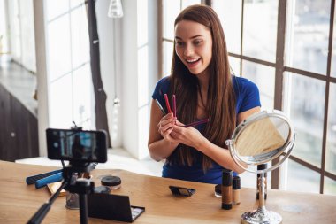 Evde kamera çekim yaparken kozmetik kullanarak genç güzel kadın blogger