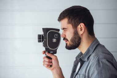 Genç duygusal bir adam arka planda eski bir kamerayla çekim yapıyor.