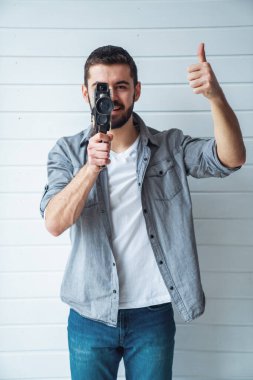 Genç duygusal bir adam arka planda eski bir kamerayla çekim yapıyor.