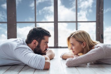 Genç mutlu çift, erkek ve kız büyük bir panoramik pencerenin önünde birbirlerine bakıyorlar.