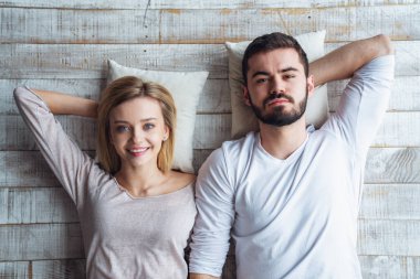 Genç, mutlu sevgili sevgili sevgili, yerde yatıp kameraya bakıyor. Üst görünüm