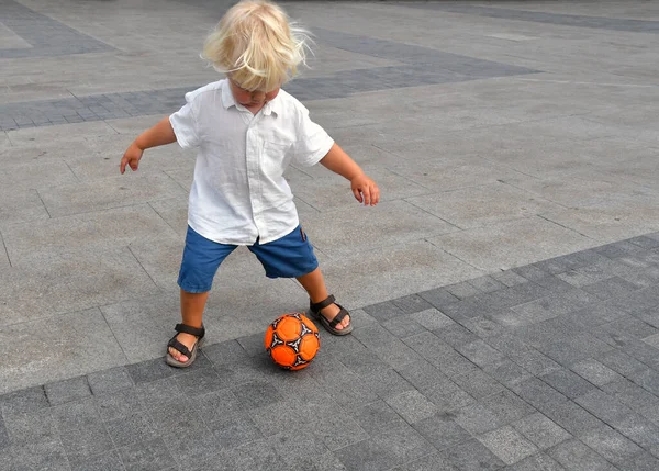 小男孩在镇上广场踢足球 夏天带着球活动的孩子 — 图库照片