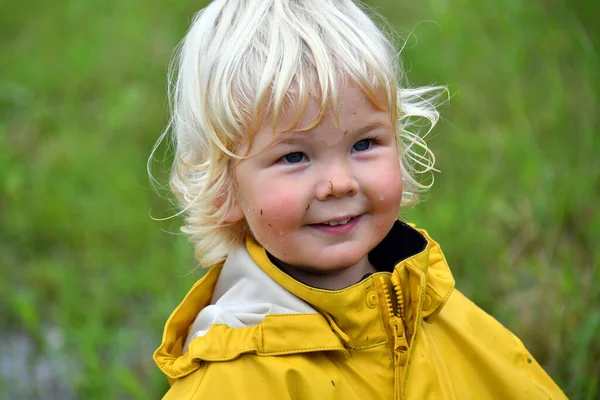노란색 비옷을 얼굴에 스플래시 귀여운 소년의 초상화 — 스톡 사진