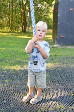 Orman oyun parkında salıncakta sallanan küçük şirin bir çocuğun portresi. Çocuklar için açık hava spor aktiviteleri