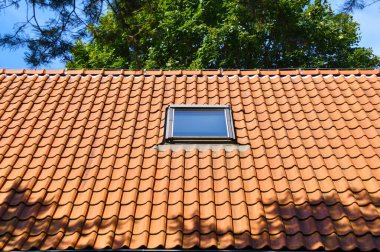 Kırmızı seramik kiremitlerin çatı katındaki tavan penceresi. Skylights Ev Tasarımı Fikirleri Harici.