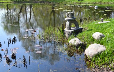 Bataklık gölü ve taş süslemeleri olan eski bir Japon bahçesi.
