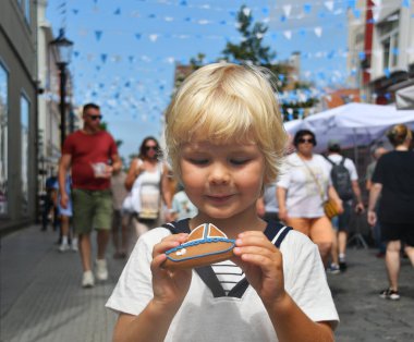 Klaipeda, Litvanya - 26 Temmuz 2025: Deniz festivali pazarında kurabiye gemisi tutan küçük çocuk. Litvanya, Klaipeda 'da yıllık kutlama.