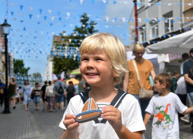 Klaipeda, Litvanya - 26 Temmuz 2025: Deniz festivali pazarında zencefilli ekmek taşıyan küçük bir çocuk. Litvanya, Klaipeda 'da yıllık kutlama.