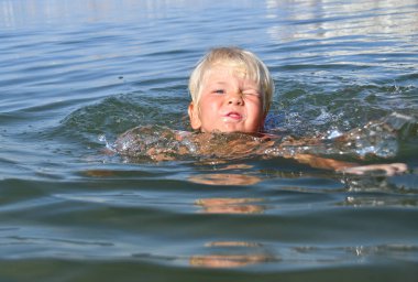 Genç bir çocuk güneşli bir yaz gününde Akdeniz 'de yüzüyor. Suyun ve dalgaların tadını çıkarıyor.