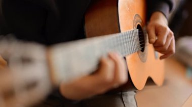 Erkek elleri gitar tellerini tıngırdatıyor, bir müzik yaratıcılığı anı
