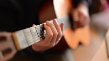 Gitar çalan bir adamın elleri, her akorla müziği canlandırıyor.