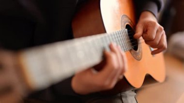 Bir adam müzik anında gitar tellerini nazikçe tıngırdatır.