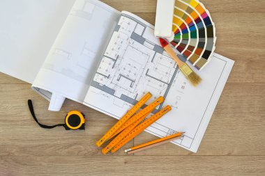 Architectural drawings with color guide, brushes, pencils, ruler on wooden background. Top view. Repair housing concept.