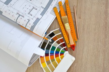Architectural drawings with color guide, brushes, pencils, ruler on wooden table. Top view. Repair housing concept.