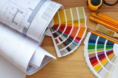 Architectural drawings with color guide, brushes, pencils, ruler on wooden table. Top view. Repair housing concept.