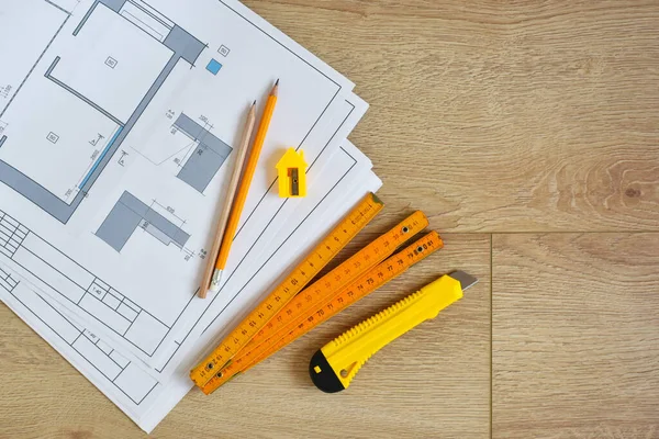 Architectural drawings and pencils, ruler, clerical knife on wooden background. Top view. Repair housing concept.