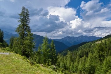 Dağların üzerinde fırtına bulutları. Yeşil çayırlar, dağınık yerleşim yerleri ve etkileyici ve ilginç bulutların altında karanlık ormanlar..